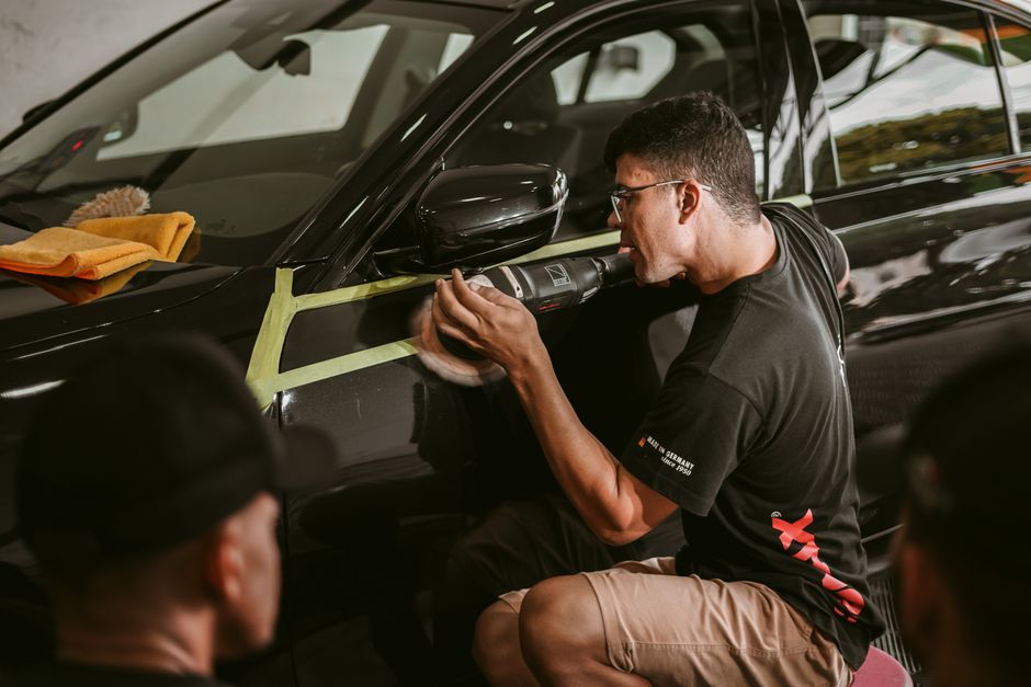 Professional auto detailer meticulously inspecting and polishing a vehicle exterior